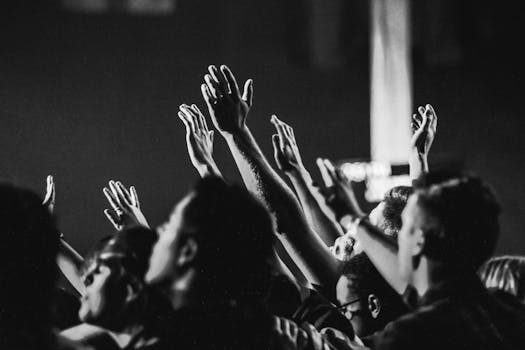 pexels-photo-1666816-1666816 Dynamic black and white photo of a concert audience with hands raised, capturing the energy of live music.