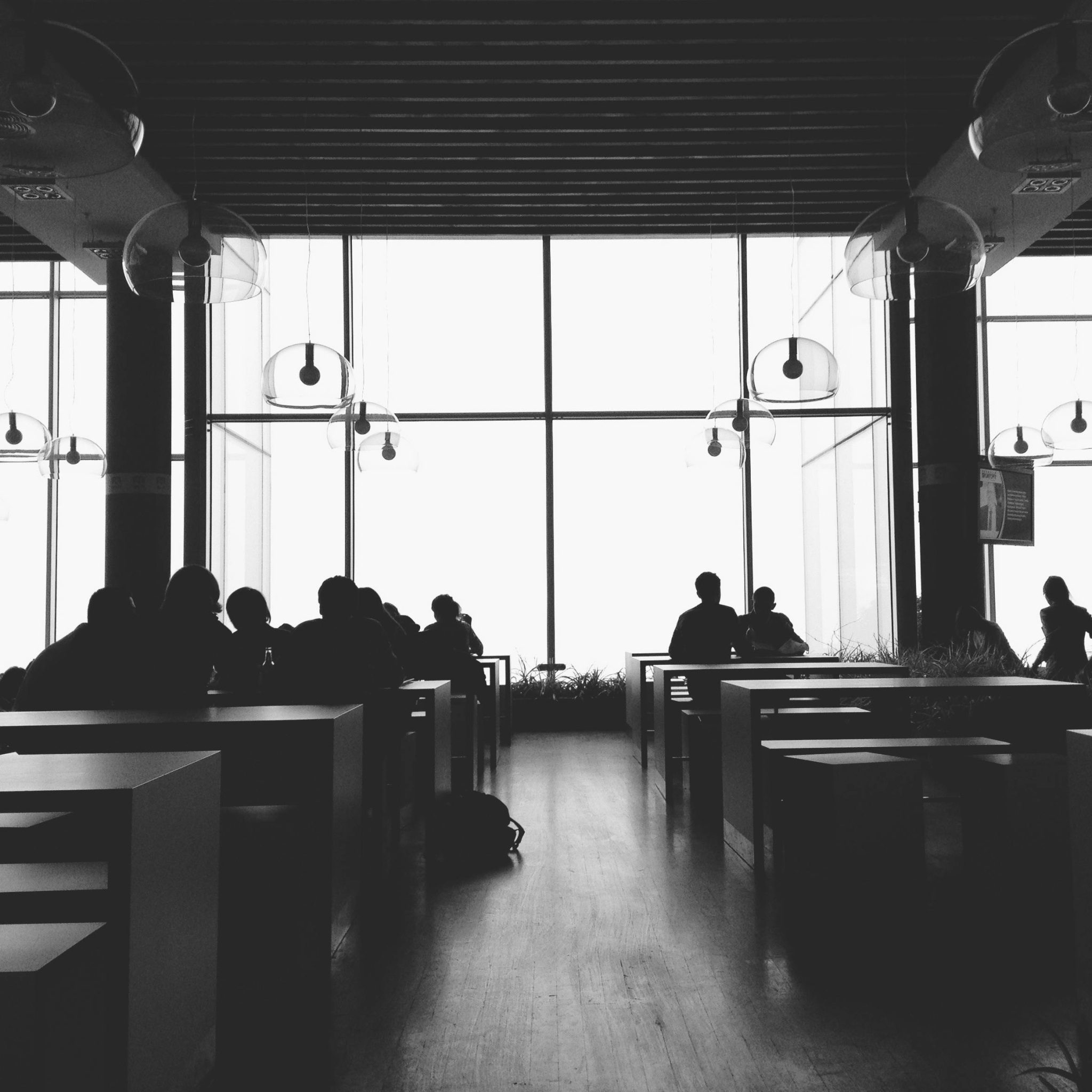 pexels-photo-52576-52576 Black and white silhouette of people sitting and chatting in a modern cafeteria.